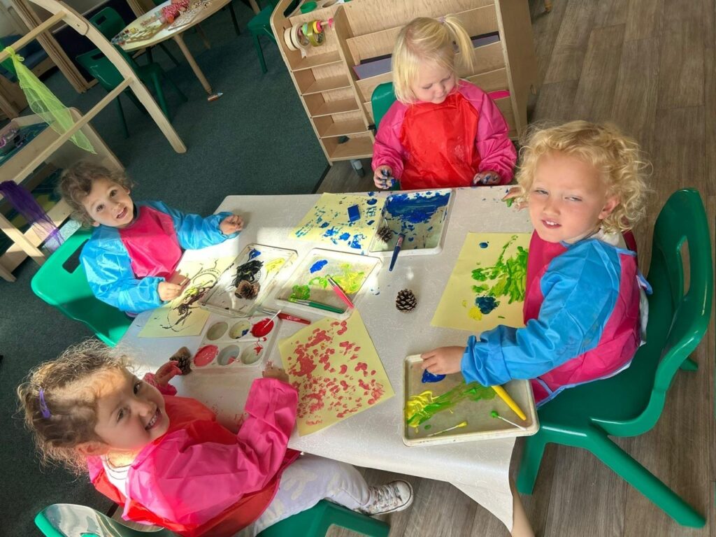 Nursery children painting together at a table
