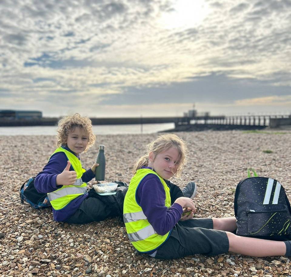 Pupils sitting on the shingle during a beach school session